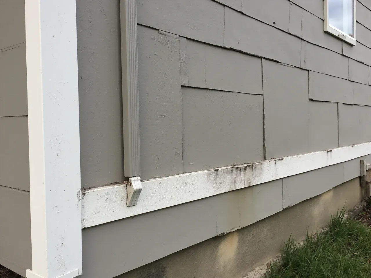 Damaged and faded fiber cement siding before replacement